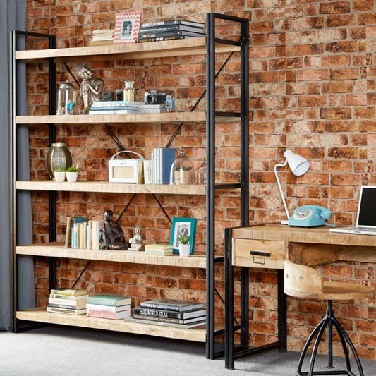 Office desk and bookshelf against brick wall.