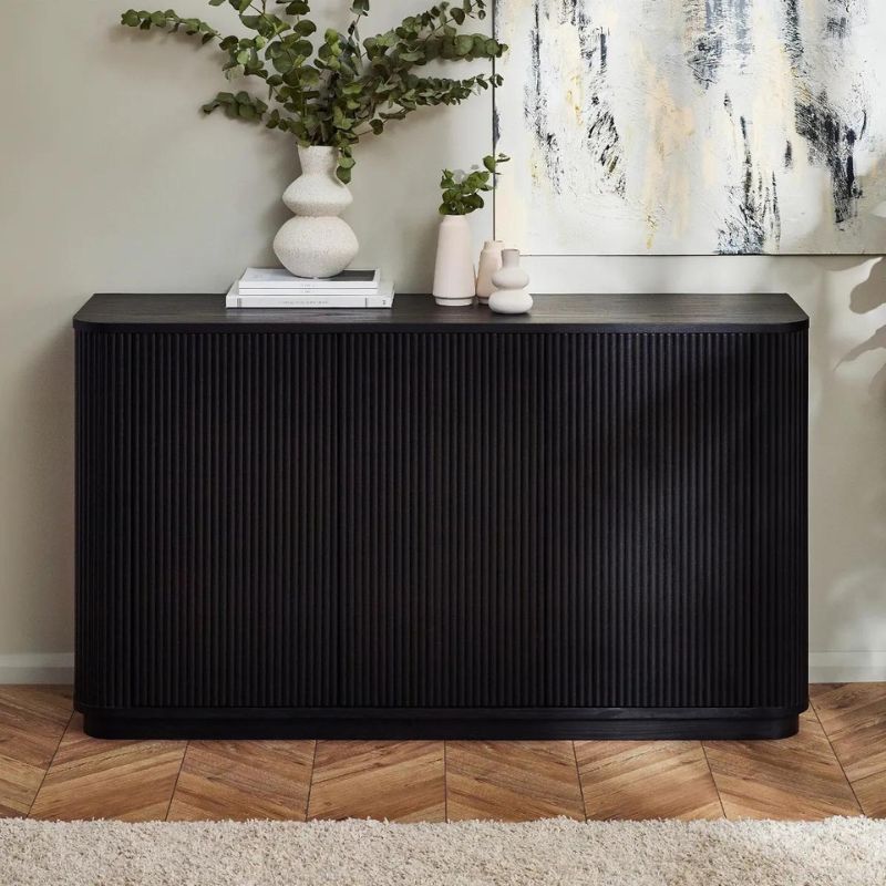 A sleek black sideboard featuring a vibrant green plant elegantly placed on top, enhancing the modern decor.