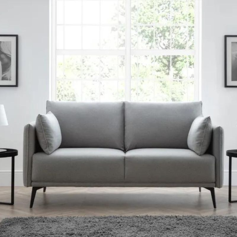 A grey sofa positioned in a well-lit room featuring a large window, creating a cozy and inviting atmosphere.