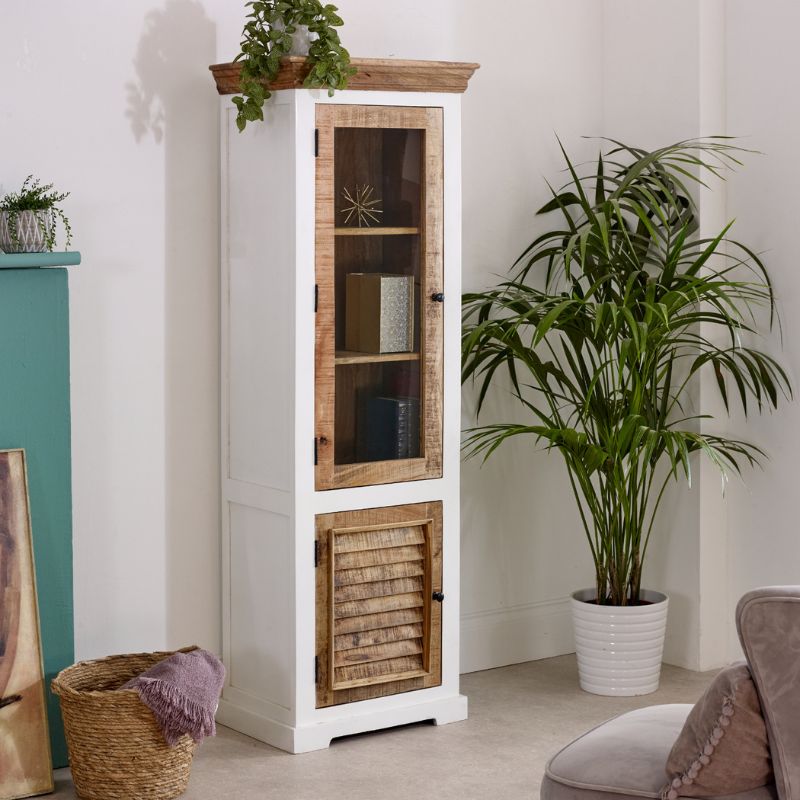 A white and wooden bookcase stands in a room, with a green plant positioned in the corner beside it.