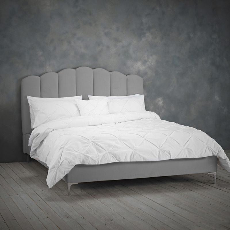 A bed featuring a white headboard set against a stylish grey wall, creating a modern and serene bedroom atmosphere.