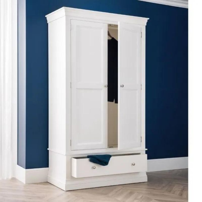 A white wardrobe featuring drawers stands against a blue wall, creating a stylish and modern interior design element.