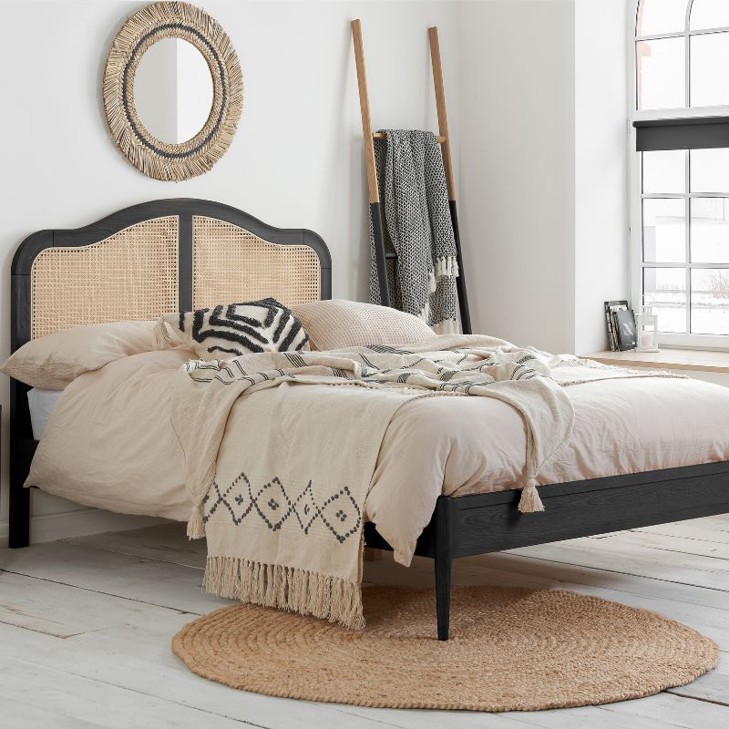 A black-framed bed with a white rug underneath.