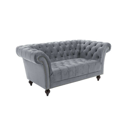 A grey velvet chesterfield sofa featuring a classic buttoned back design, exuding elegance and sophistication.