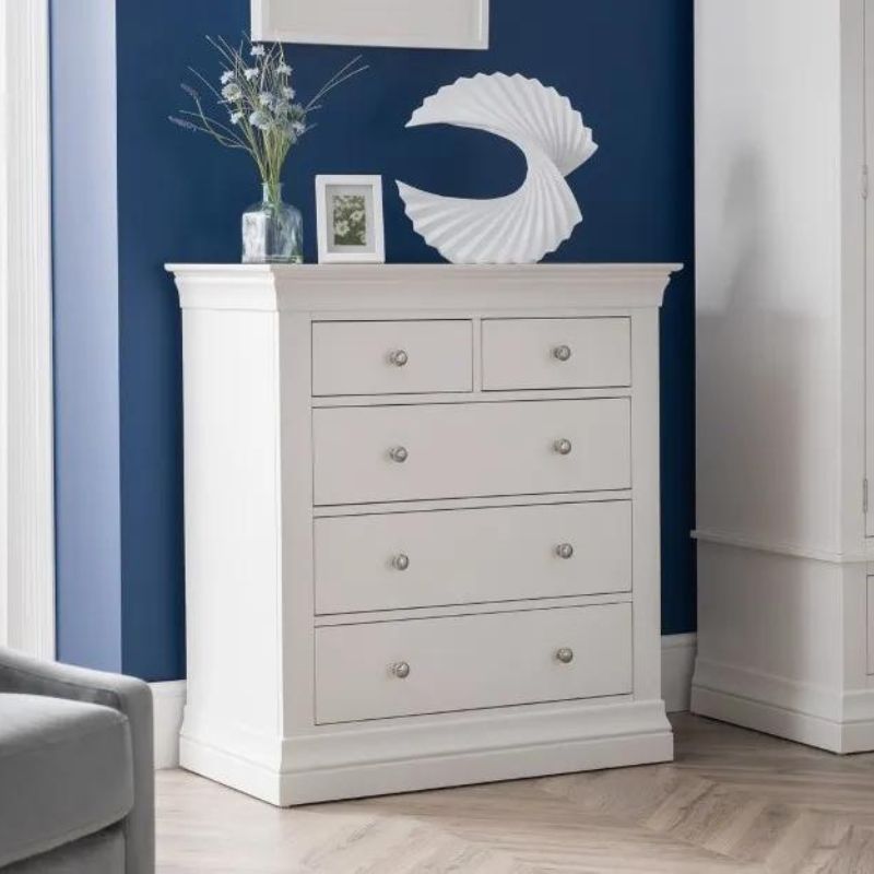 A white chest of drawers positioned in a room adorned with blue walls, creating a serene and stylish atmosphere.