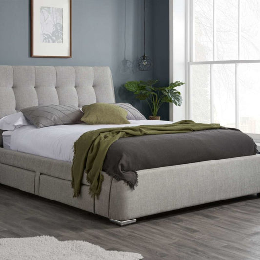 A bed with a grey headboard and a green blanket.